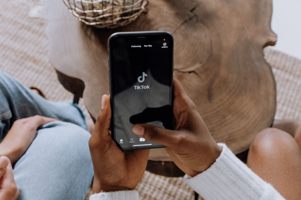 Hand holding smartphone with TikTok app open ready to create BookTok content for book marketing