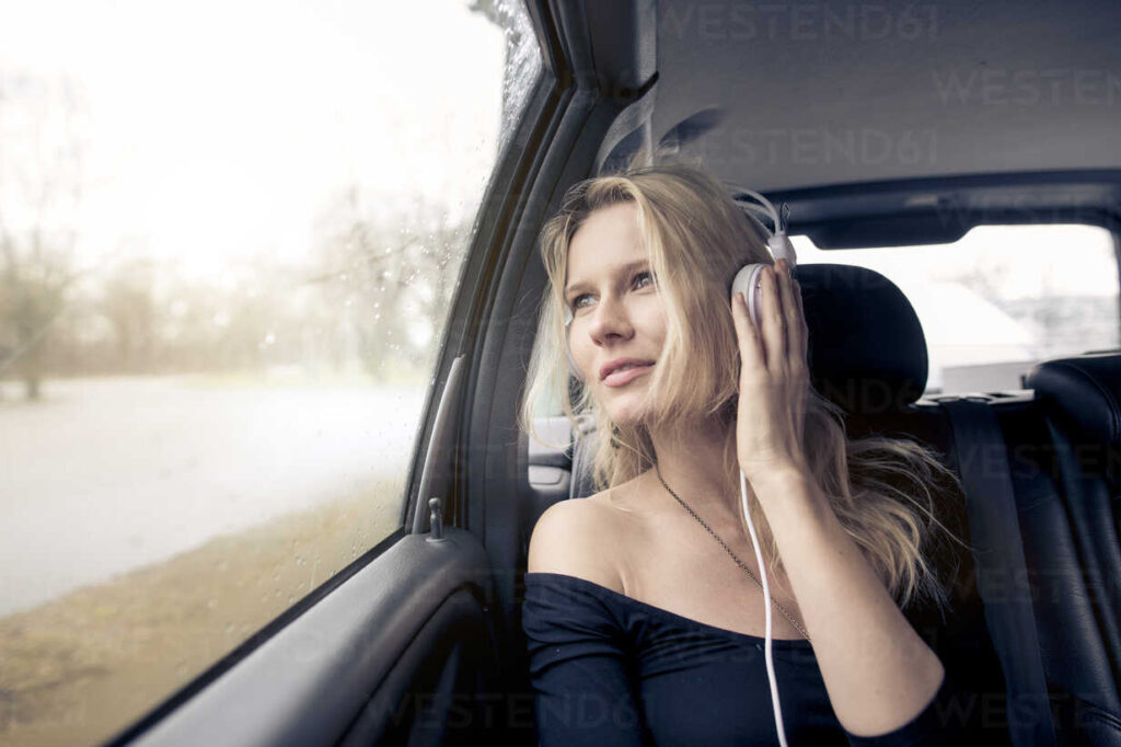 Woman listening to an audiobook on headphones while seated in a car showing the market opportunity.