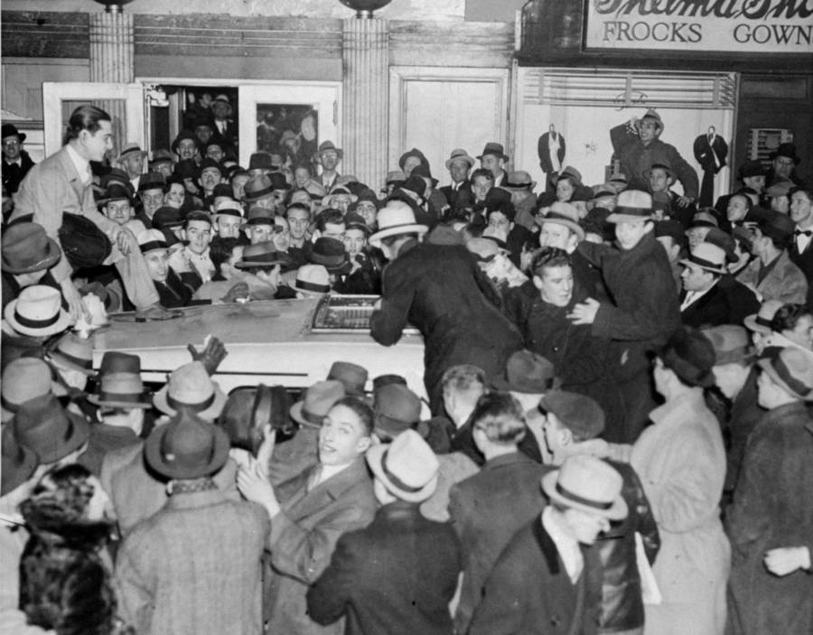 Crowded street scene from 1920s Harlem Renaissance era showing African American community members in period clothing outside entertainment venues, illustrating the vibrant jazz age culture