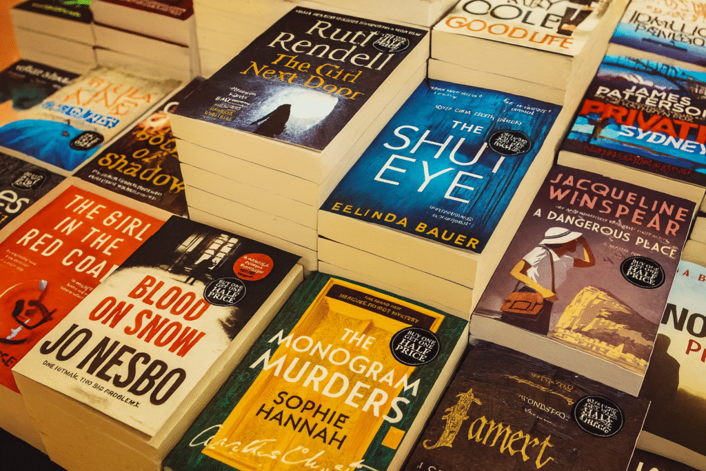 Stack of mystery and thriller paperback books including titles by Jo Nesbø and Sophie Hannah on wooden table