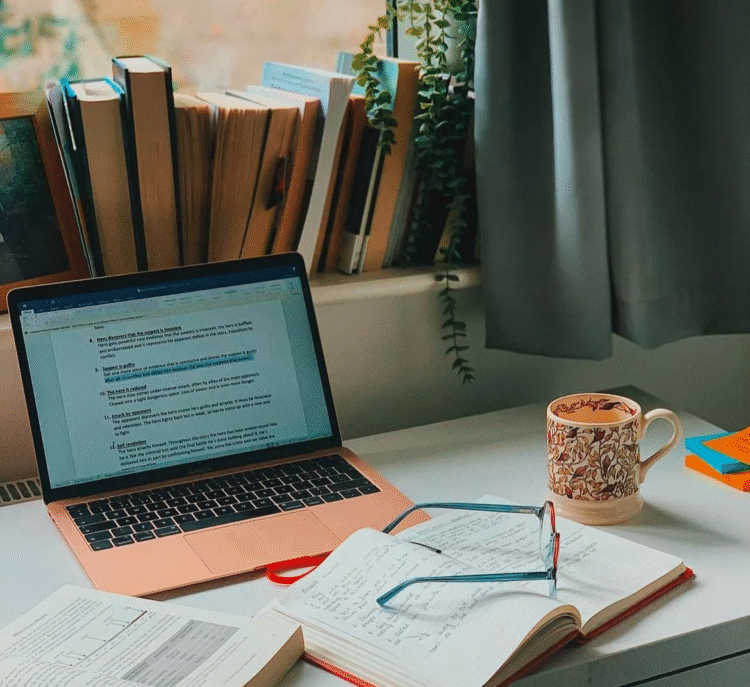 Author writing at desk with laptop, notebooks, and coffee in natural lighting workspace perfect space for email marketing for authors
