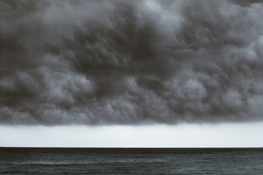 Dramatic dark storm clouds gathering over calm water creating foreboding atmosphere perfect for suspense and horror writing