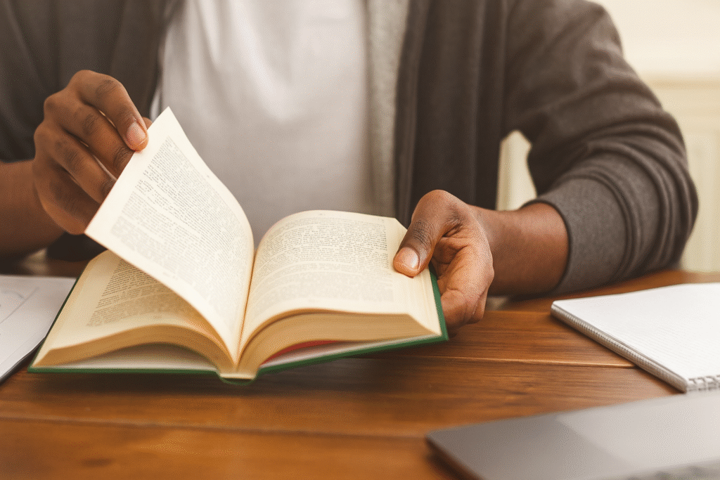 Reader's hands turning pages of an open book on wooden table, showing engagement