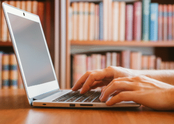 Author typing book metadata on laptop in library workspace for improved discoverability