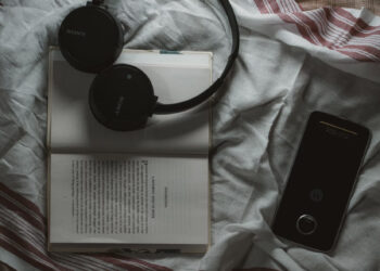 Headphones resting on open book representing audiobook narration and AI voice technology for indie authors