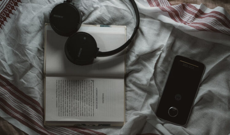 Headphones resting on open book representing audiobook narration and AI voice technology for indie authors