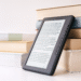 Stack of physical books placed next to a digital tablet e-reader, illustrating the paper versus screen reading comparison
