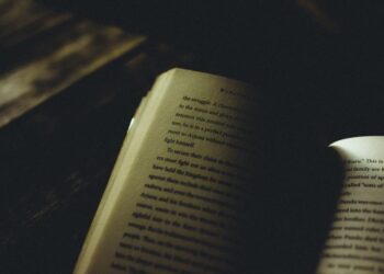 Open book in moody atmospheric darkness with selective lighting, symbolizing the tension and mystery that effective cliffhangers create