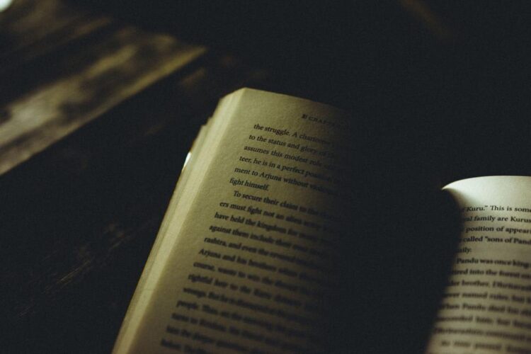 Open book in moody atmospheric darkness with selective lighting, symbolizing the tension and mystery that effective cliffhangers create