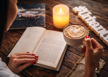 Cozy reading moment with coffee and book on sunlit table creating inviting atmosphere