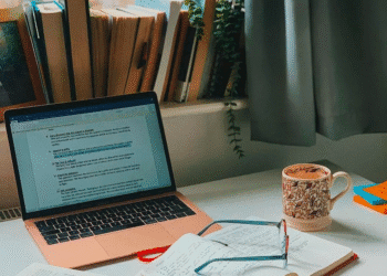 Author writing at desk with laptop, notebooks, and coffee in natural lighting workspace perfect space for email marketing for authors