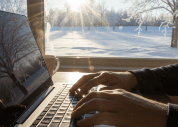 A dynamic first-person perspective of hands typing quickly on a laptop against a bright, crisp winter morning backdrop, symbolizing writing momentum.